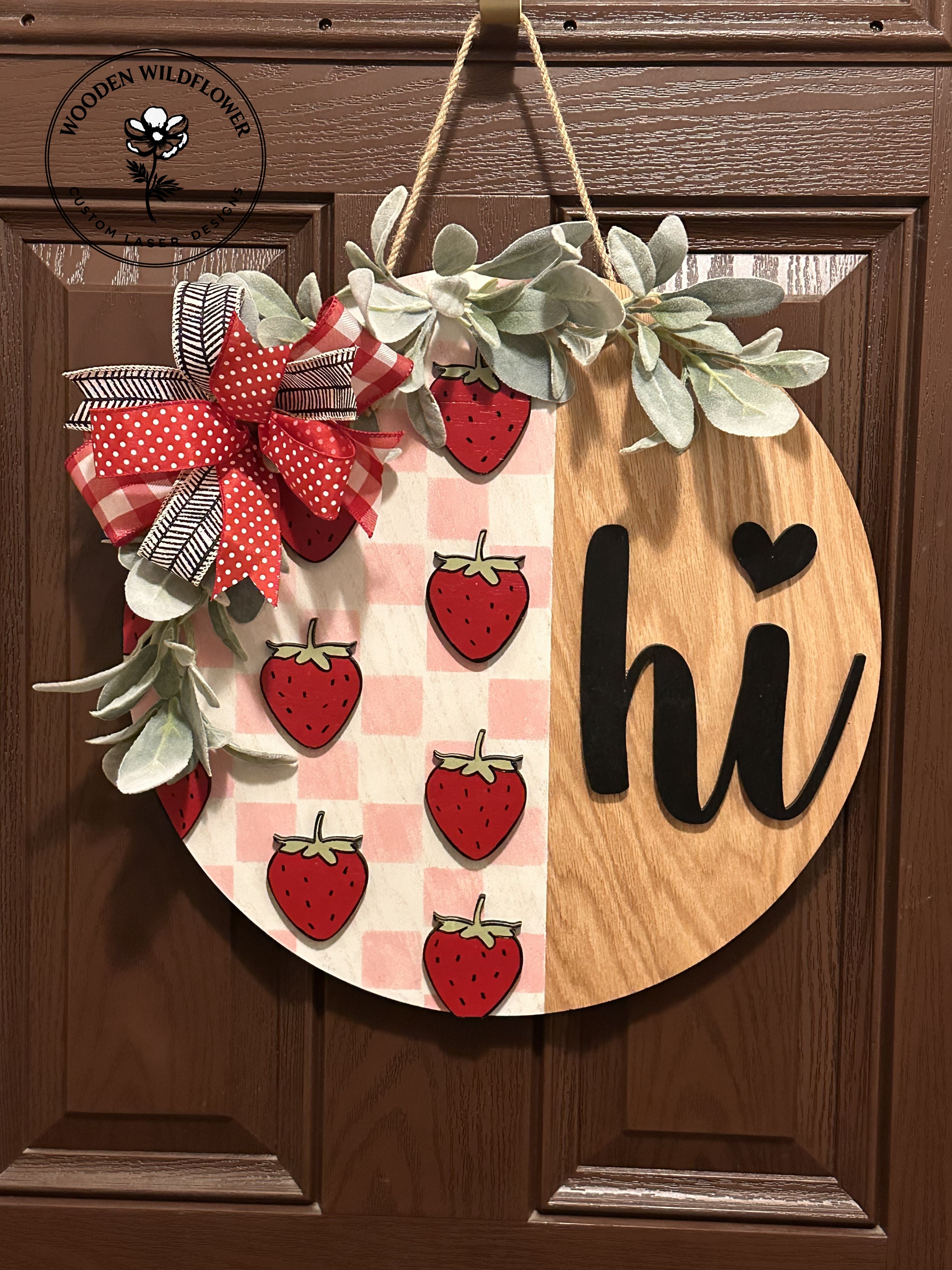 Decorative door hanger with strawberries, plaid pattern, and 'hi' text on a wooden background.